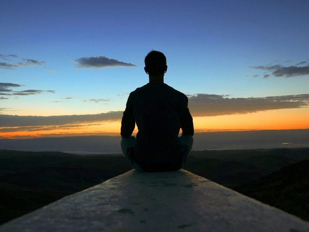 Férfi napfelkelte előtt a szabad ég alatt meditál